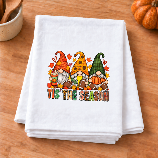 Upright Football Gnomes Tis The Season design on folded white towel on a fall kitchen wood countertop