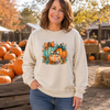 Woman wearing a sand sweatshirt with aqua and orange pumpkins, bows and flowers