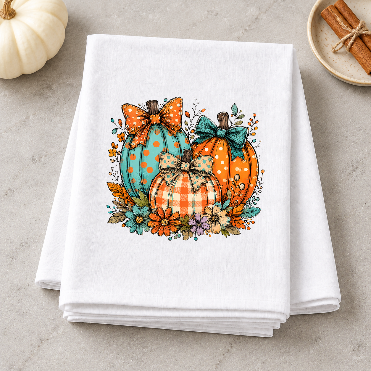 Boho aqua and orange pumpkins with bows and flowers on a folded white kitchen towel