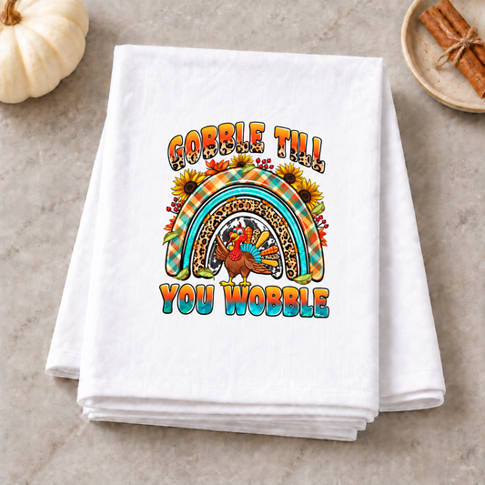 Gobble Til You Wobble turkey rainbow design on folded white towel in a fall spice kitchen scene
