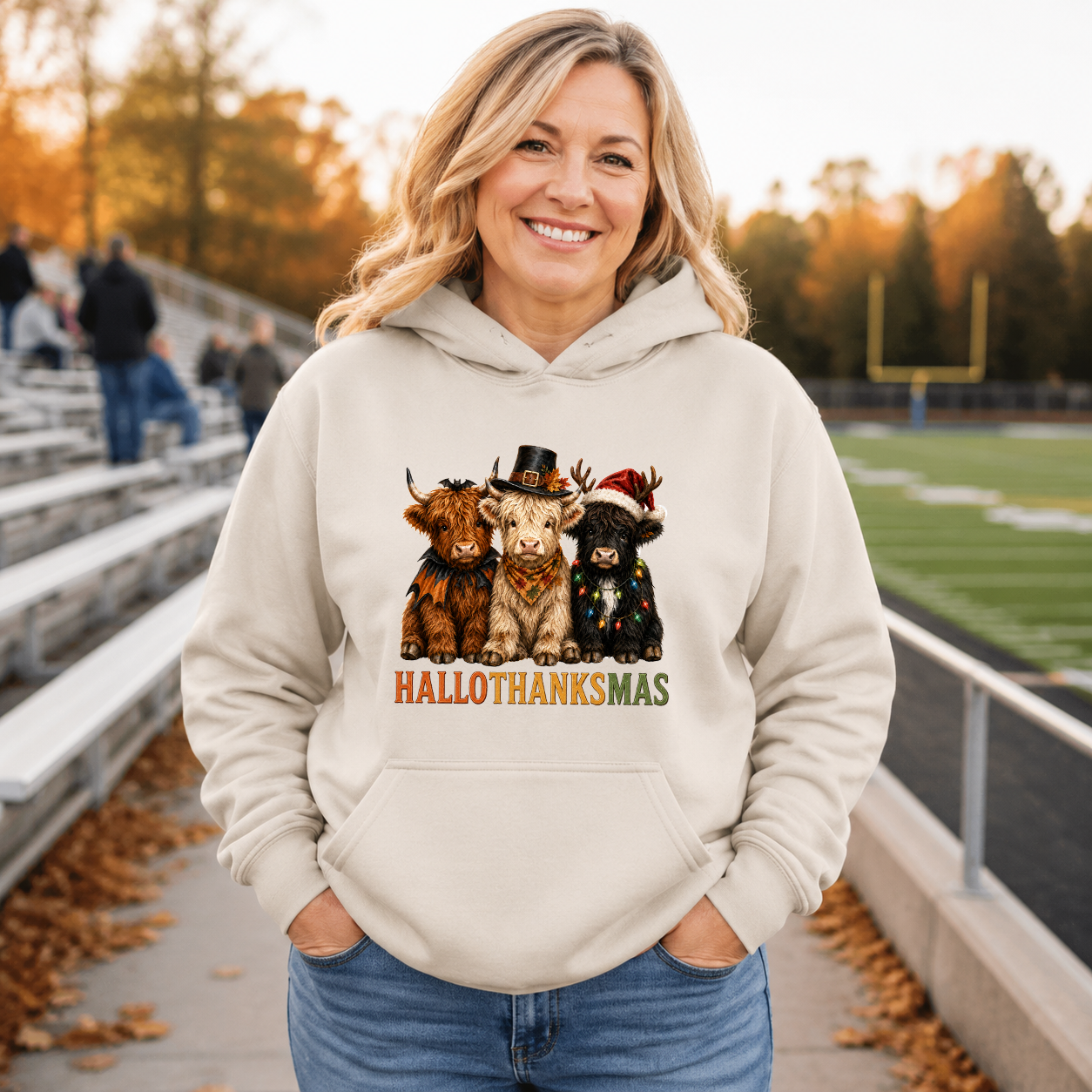 Woman wearing a sand hoodie with Halloween Thanksgiving and Christmas Highland cows