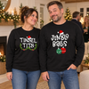 Couple wearing Tinsel Tits and Jingle Balls designs on black long-sleeve tees at a Christmas party
